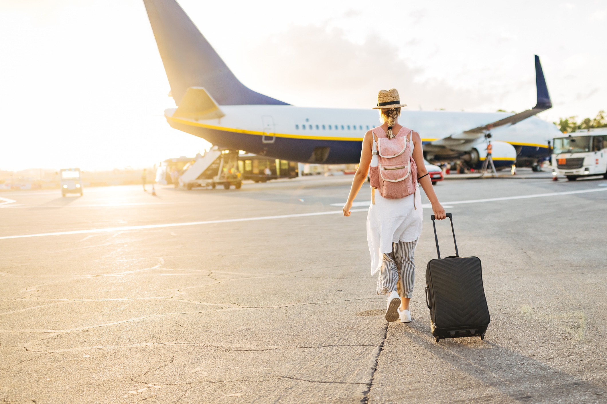 Back view of a woman walking towards the plane, ready to board and begin her vacation