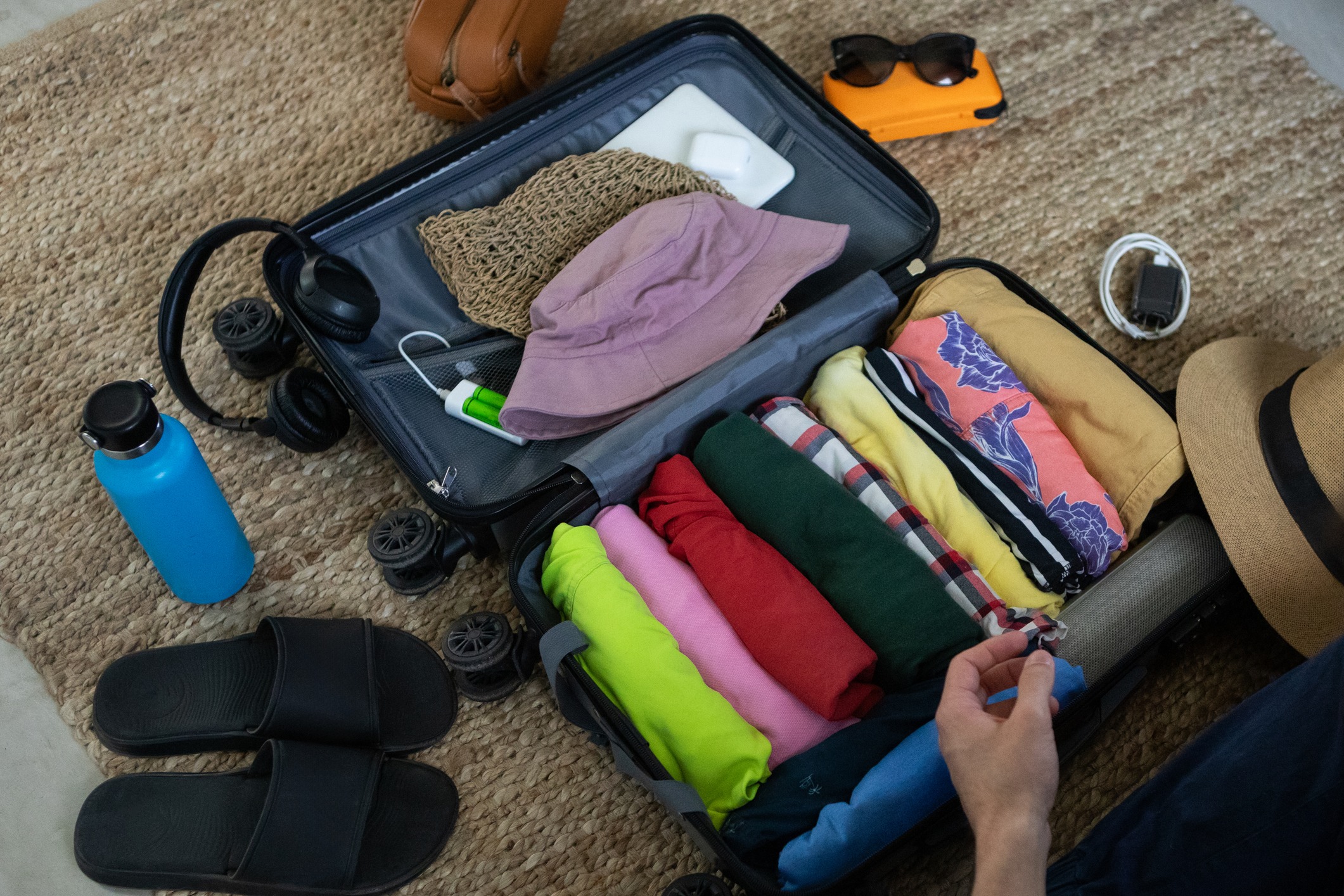 Young man packing his suitcase with clothes and travel items before going on summer vacation
